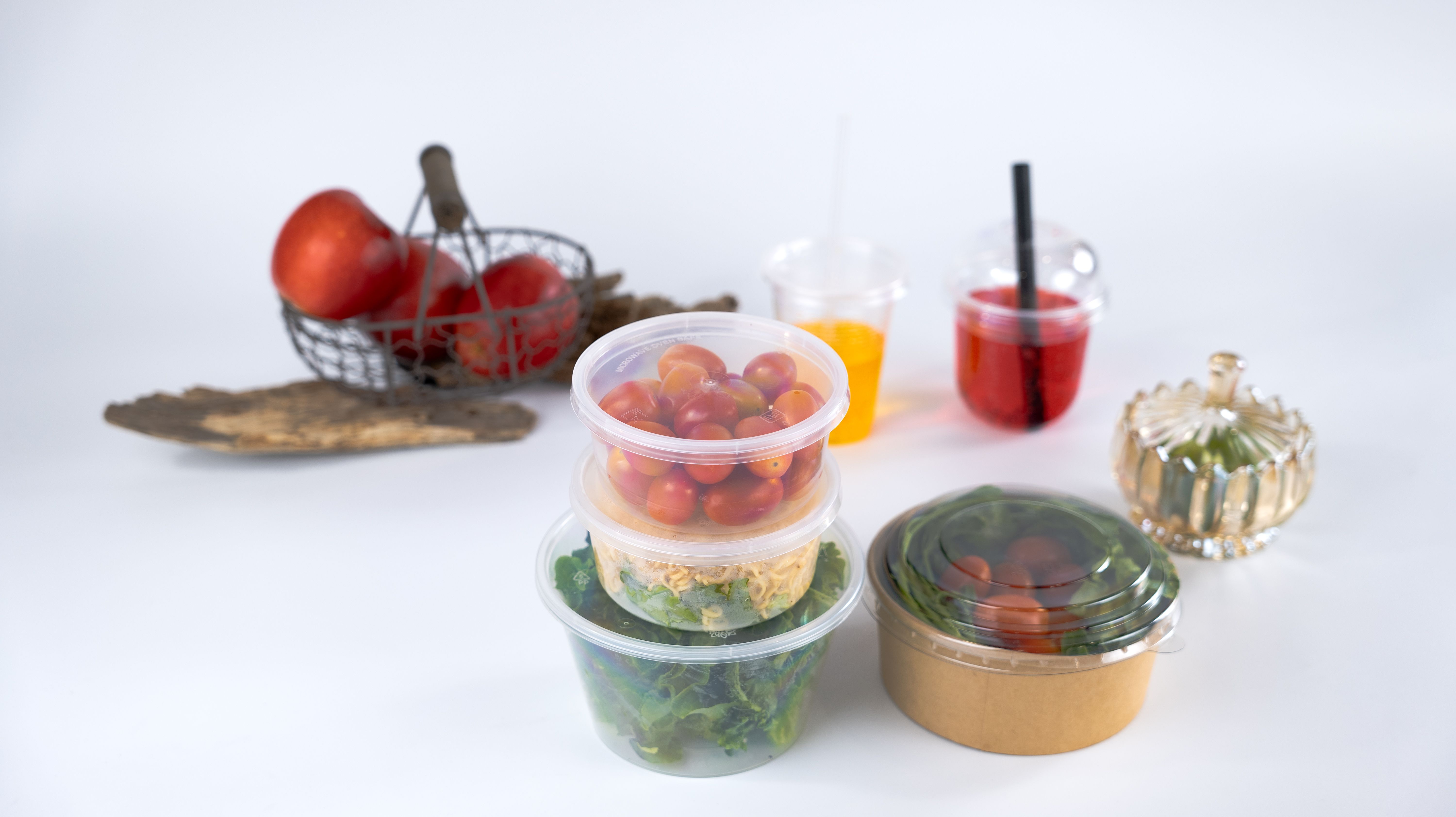 Các loại bao bì thực phẩm của VietPlastic, bao gồm ly nhựa và hộp tròn, chứa thực phẩm tươi như trái cây và salad